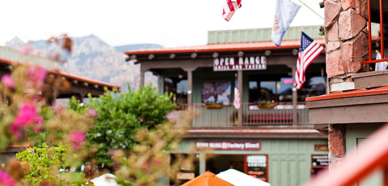 Улица города Седона с домами и флагами на фоне гор